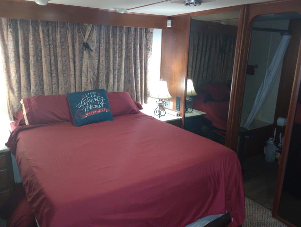 Cozy master bedroom featuring a queen-size bed with red bedding, decorative pillows, and side tables with lamps, surrounded by floral curtains.