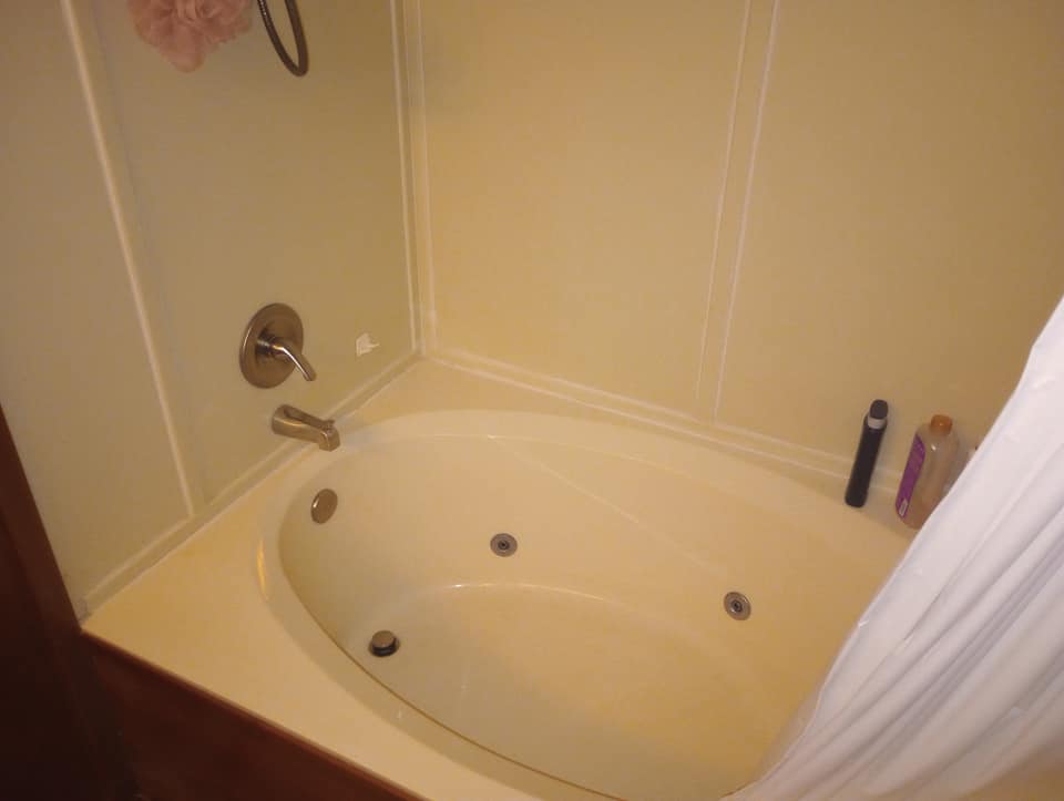 Jacuzzi tub in a bathroom setting, with a shower fixture and toiletries visible.