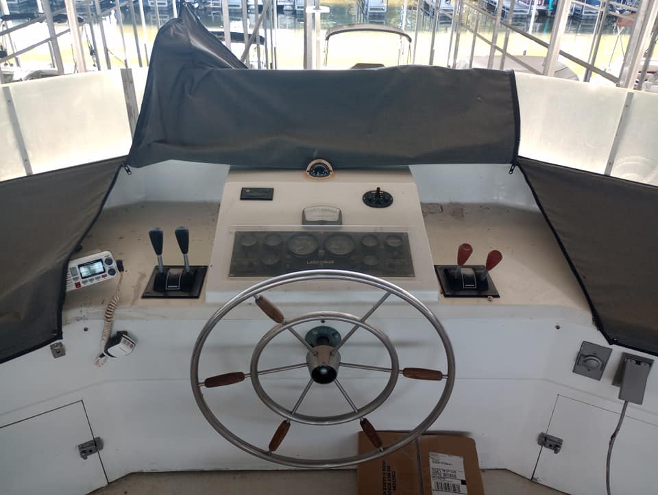 View of the control panel and steering wheel of a 1990 Lazy Days 60' houseboat, featuring throttle controls and gauges.