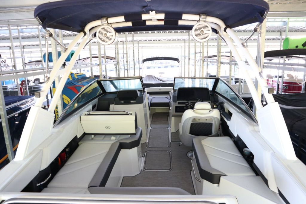 Interior view of a 2021 Cobalt R6 boat featuring spacious seating, a steering console, and an open layout, docked in a covered slip.