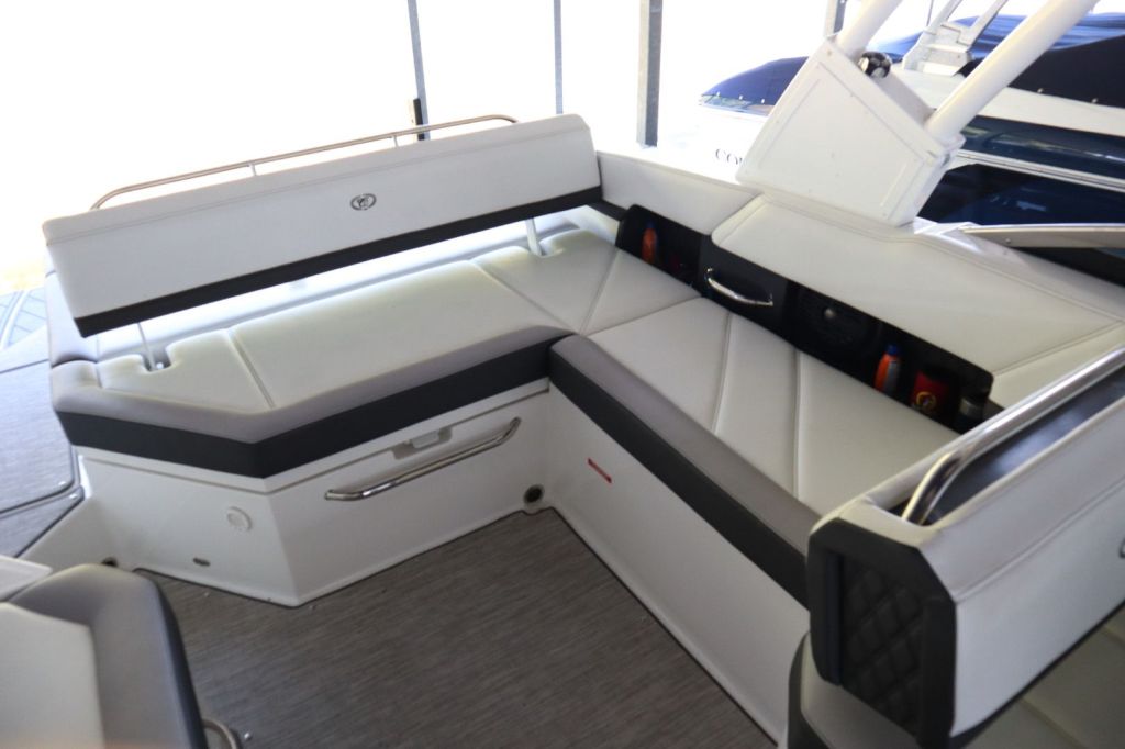 Interior seating area of a 2021 Cobalt R6 boat, featuring plush white and gray upholstery with built-in storage and audio system.