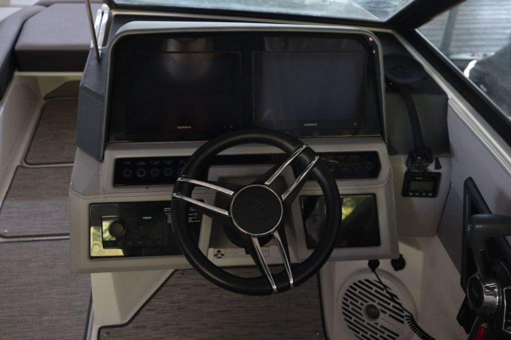 Close-up view of the helm of a 2021 Cobalt R6 boat, featuring dual digital displays, a stylish steering wheel, and various control buttons.