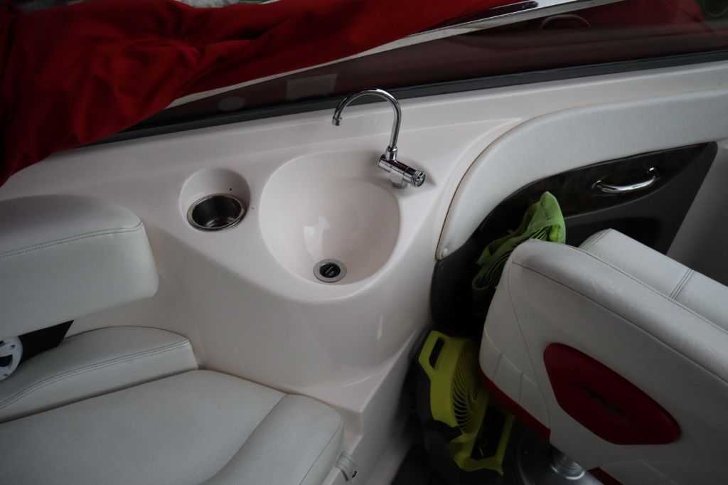 Interior view of a 2007 Regal 2400 Bowrider showing a sink and seating area, featuring white upholstery and a towel draped over the side.