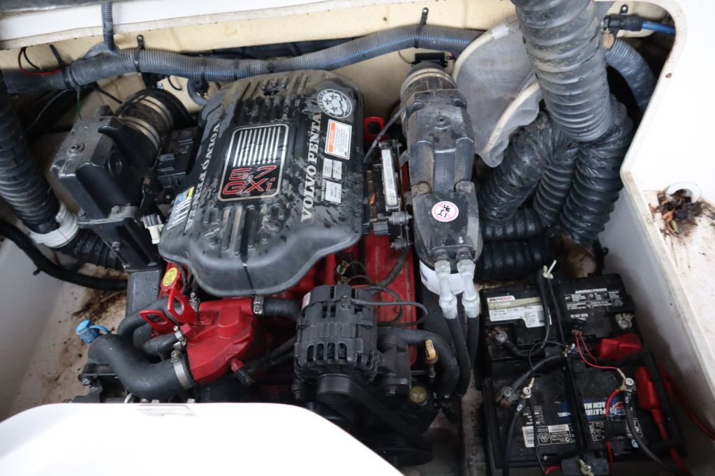 Close-up view of a Volvo Penta 5.7 GXI engine installed in a boat. The image shows the engine block, hoses, and battery setups.