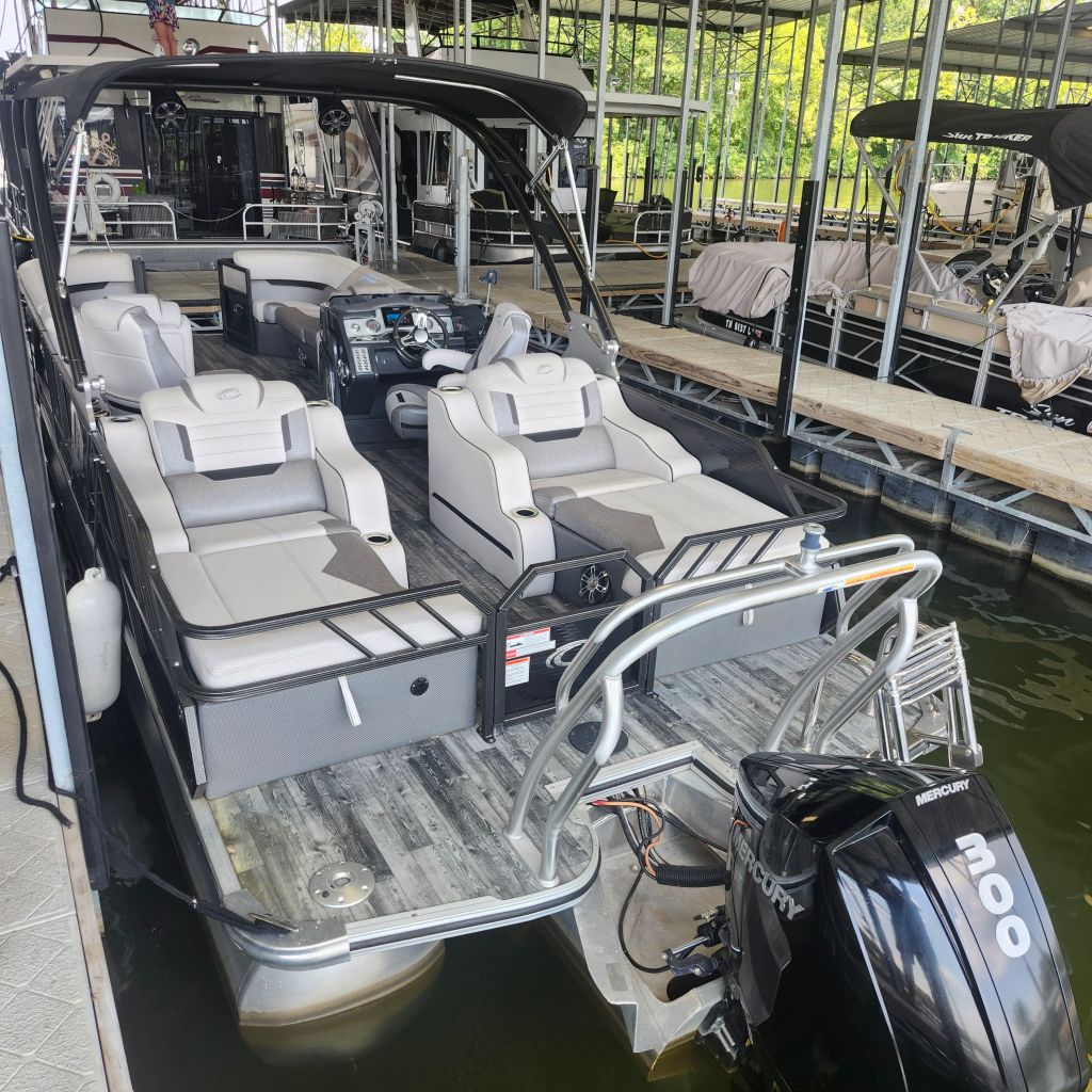 Interior view of a 2019 Crest Caliber 250 Tritoon boat with spacious seating and a Mercury 300 HP engine, located at a marina.