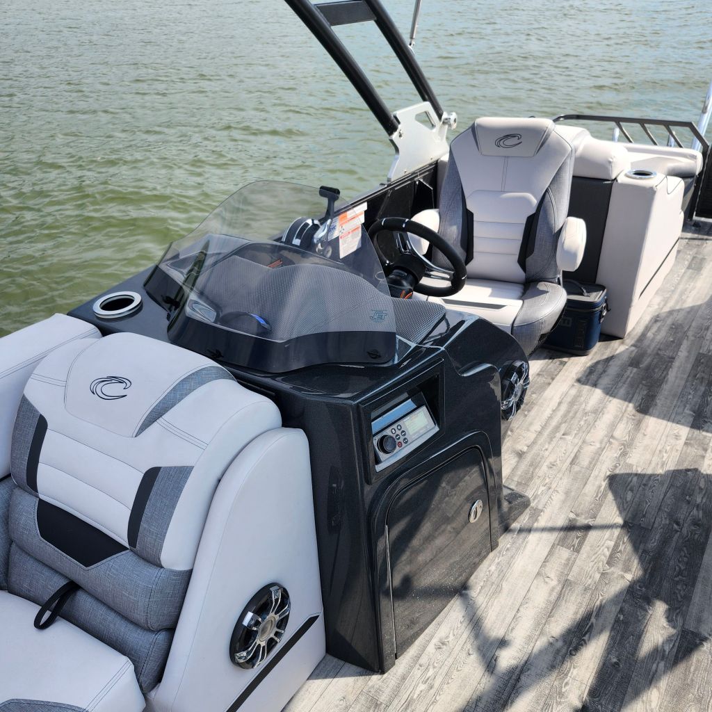 Interior view of a 2019 Crest Caliber 250 Tritoon boat showing the helm, seating, and controls.