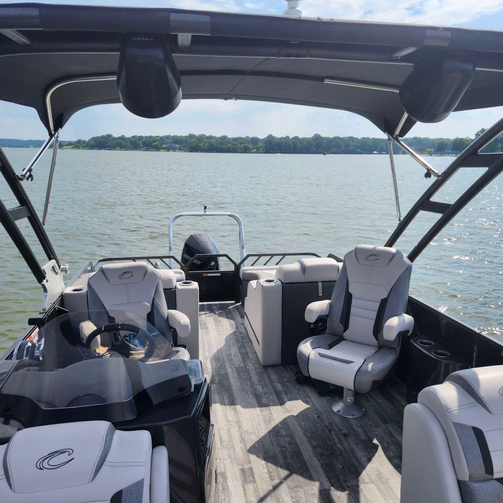 Interior view of a 2019 Crest 250 Caliber boat with spacious seating and a helm, overlooking the water.