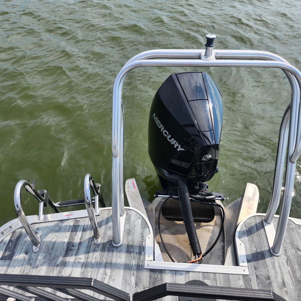 View of the back of a 2019 Crest Caliber 250 Tritoon with a Mercury outboard motor, showing a flat water surface.