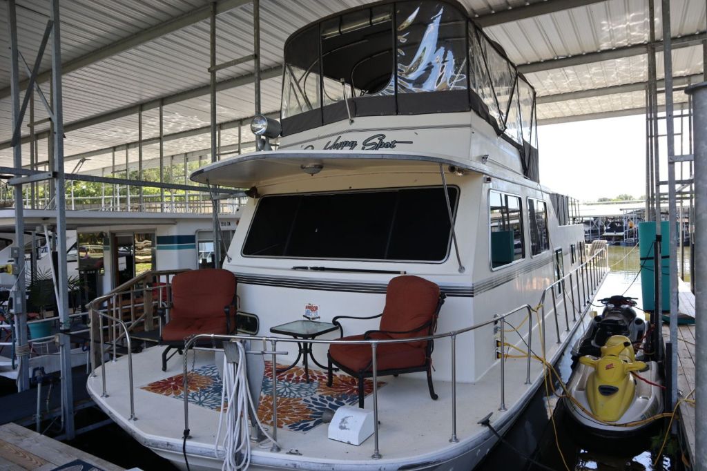 A Harbor Master 47' Widebody houseboat docked at Gallatin Marina, featuring a covered slip, outdoor seating area, and side view of the boat.