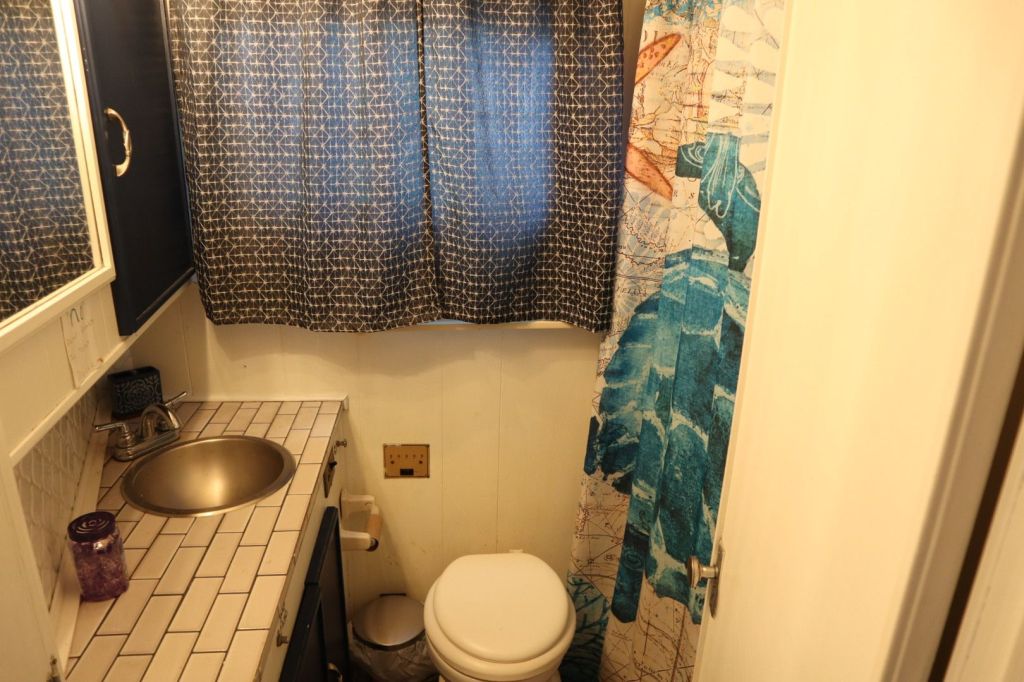 Interior view of a small bathroom featuring a circular sink, a mirror, and a decorative shower curtain with an aquatic theme.