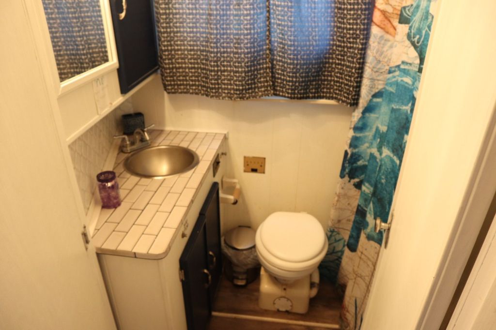 Small bathroom in a houseboat featuring a sink, toilet, and decorative shower curtain with a blue design.