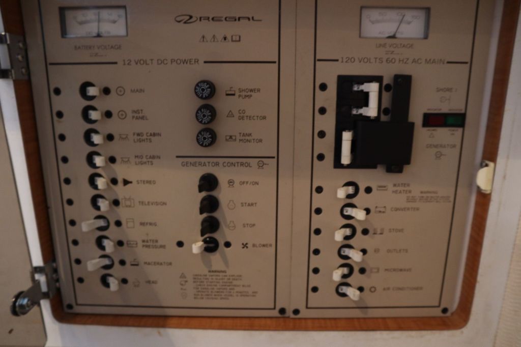 Control panel of a Regal boat, showing various switches and indicators for power, generator control, lighting, and appliances.