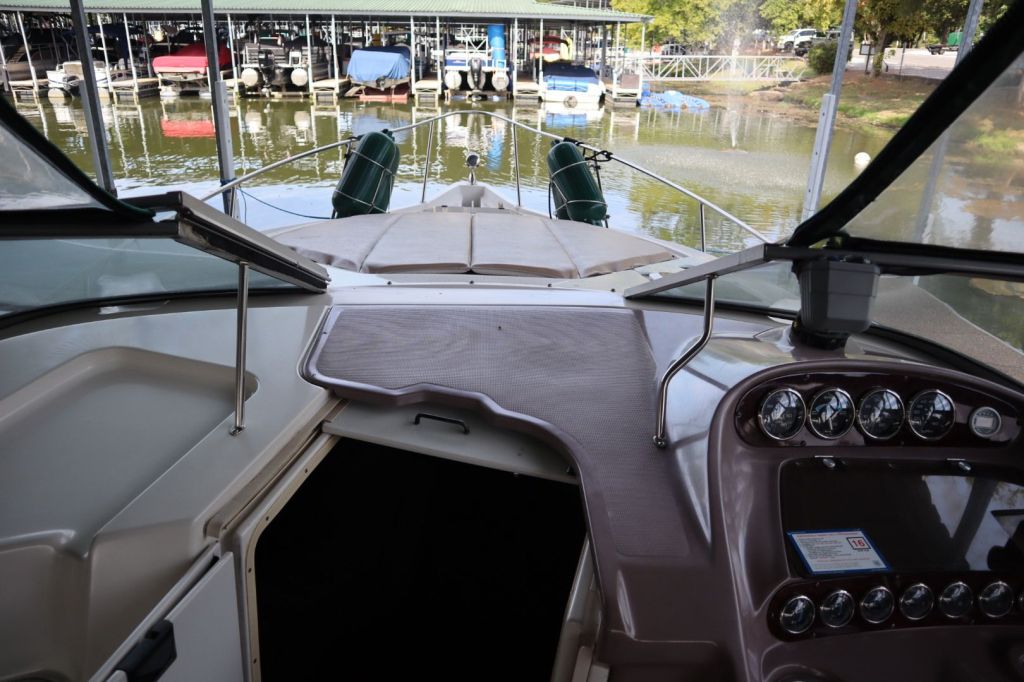 View of the helm area of a Regal 2860 Commodore boat, showcasing the dashboard with gauges and controls, with a visible cockpit area and marina in the background.