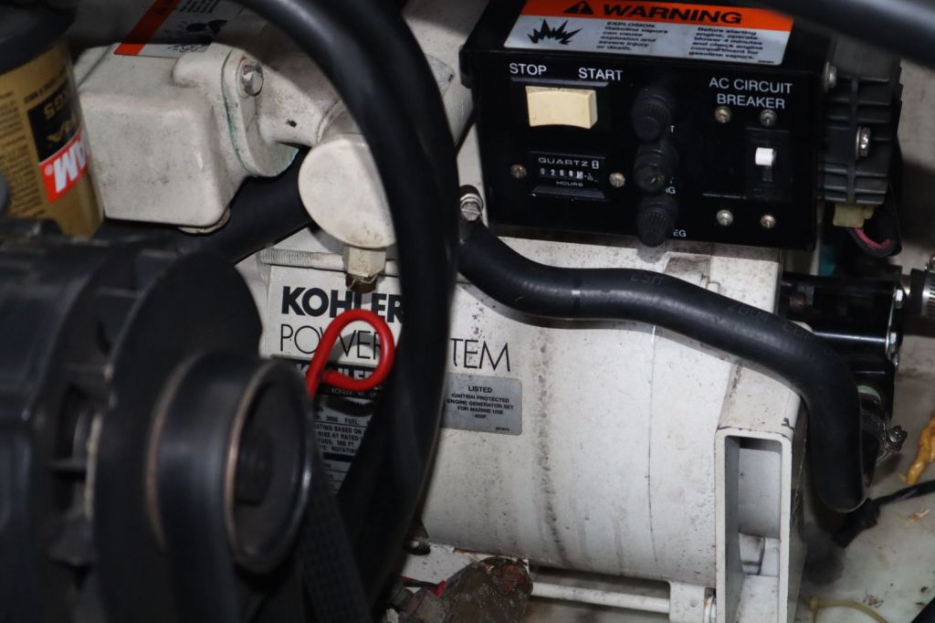 Close-up view of a Kohler marine generator with control panel and circuit breaker, located inside a boat.